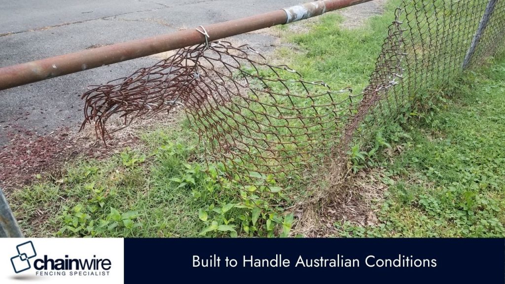 The fence is bent and broken in several places, and the ground is covered in grass and weeds.