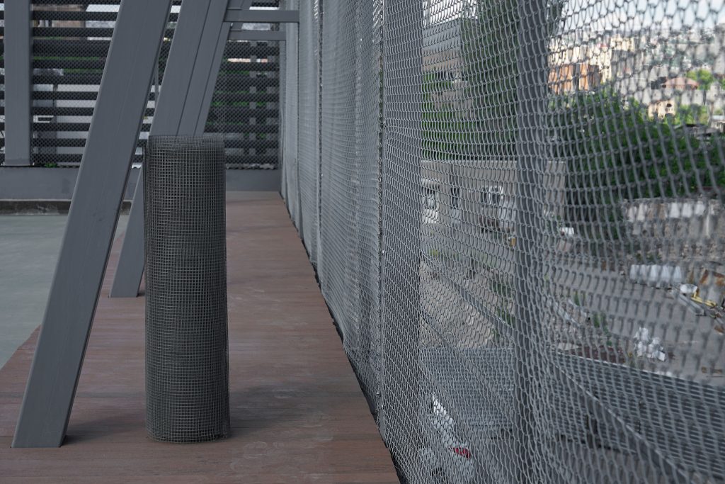 A close-up, angled view of a galvanized chain-link fence running along a wooden deck or walkway.