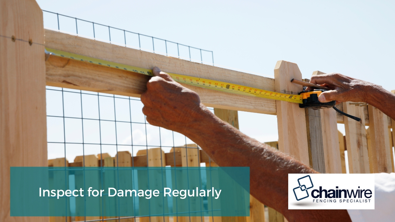 person measuring a wooden fence with a tape measure. The person is holding the tape measure in one hand and the fence post in the other. The background is a blue sky with some white clouds.