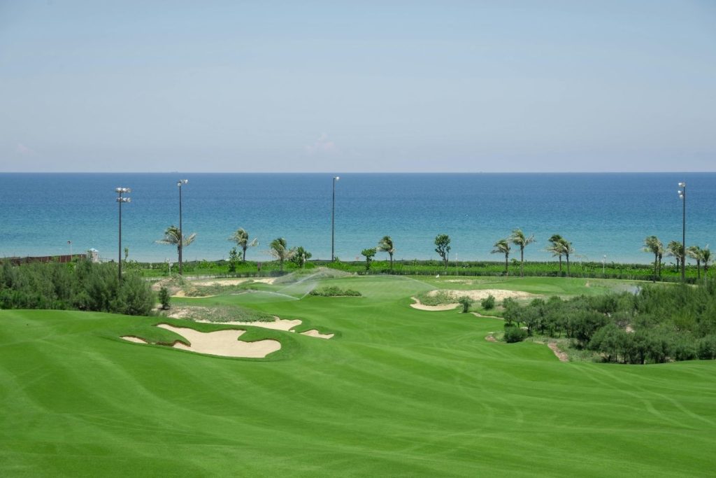 A wide view of a vibrant green golf course with manicured fairways and sand traps.